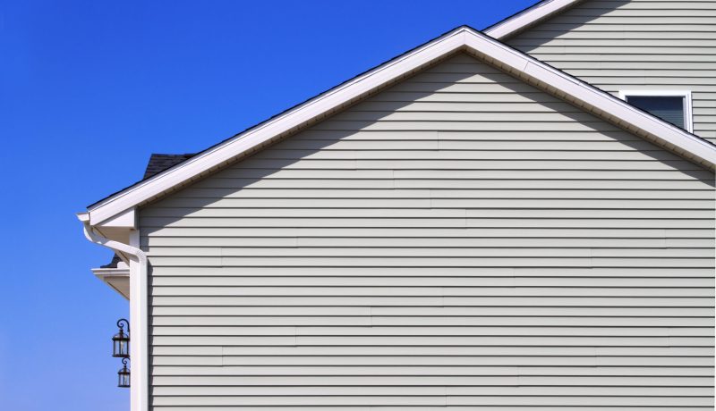 New home with gray vinyl siding and blue sky in the background